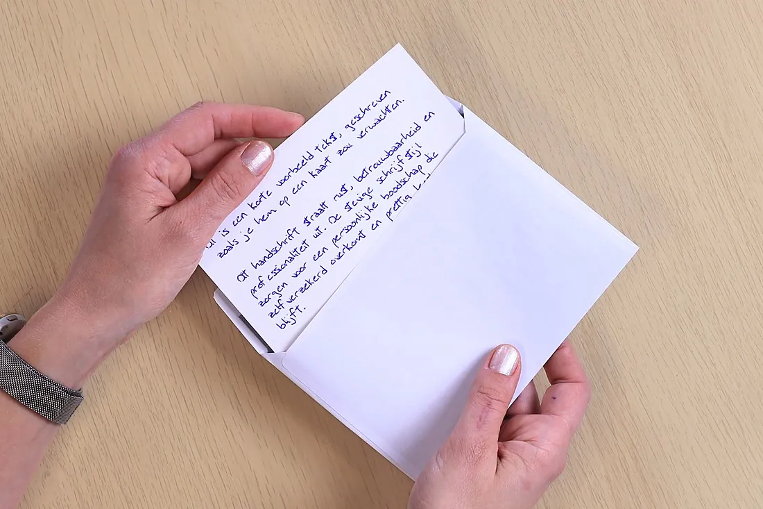Handen halen een met een echte pen geschreven kaart uit een envelop