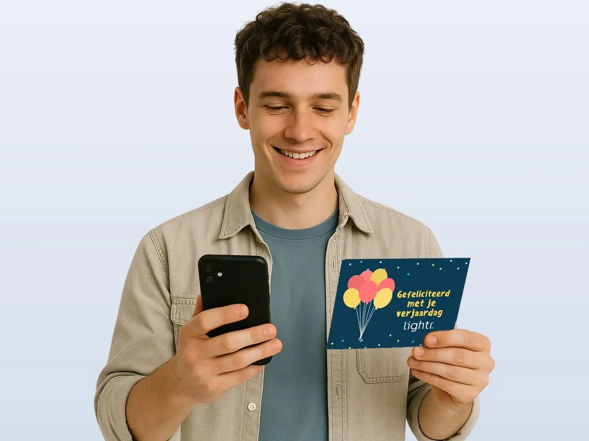 Jongeman met telefoon en een verjaardagskaart in zijn hand